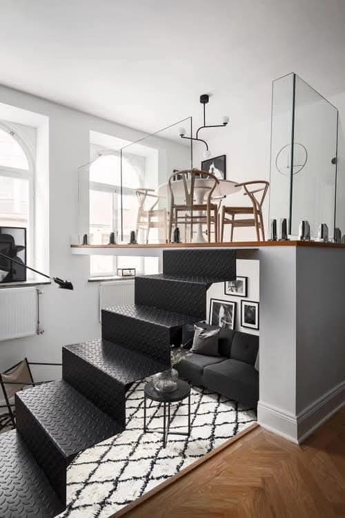 Schwarze Stahltreppe mit Glasgeländer und Holzempore in modernem Wohnloft