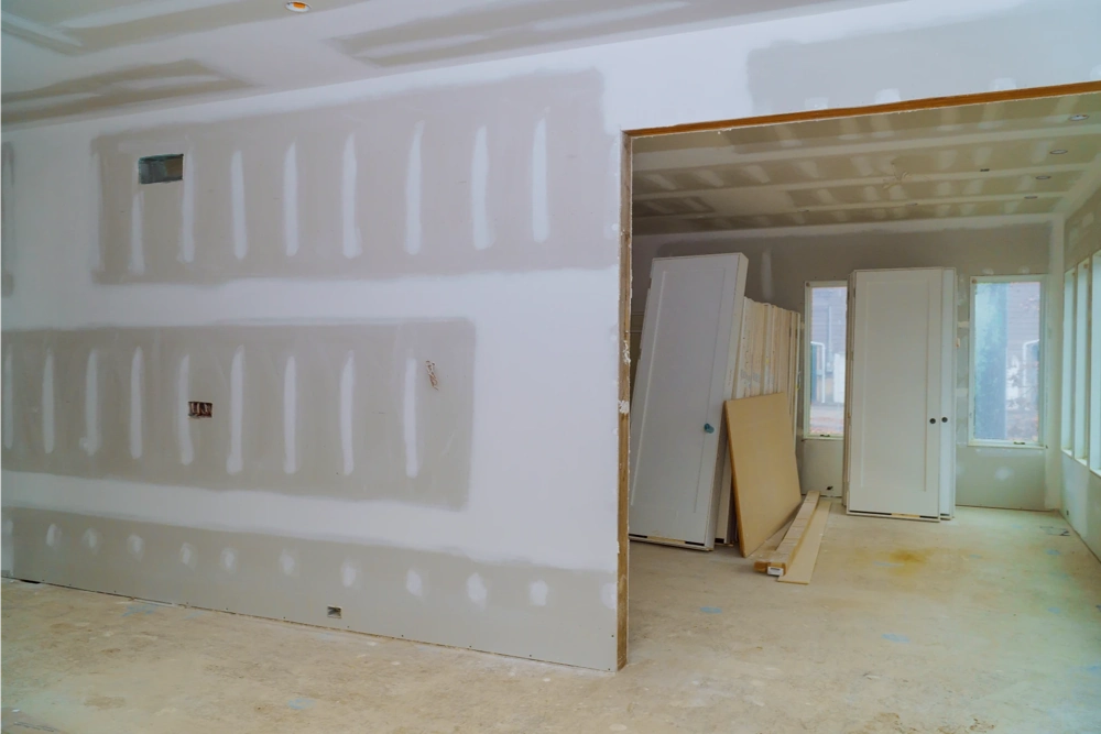 Trockenbau: noch ungespachtelte Gipskartonwände in Rohbauwohnung mit bereitgestellten Türen und Platten
